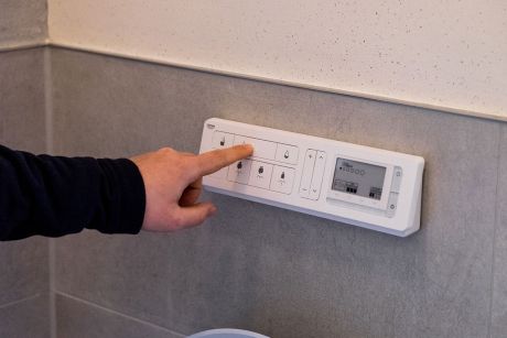 Zu sehen ist ein Techniker der auf den Thermostat der Heizung einstellungen anpasst.