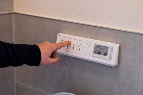 Zu sehen ist ein Techniker der auf den Thermostat der Heizung einstellungen anpasst.